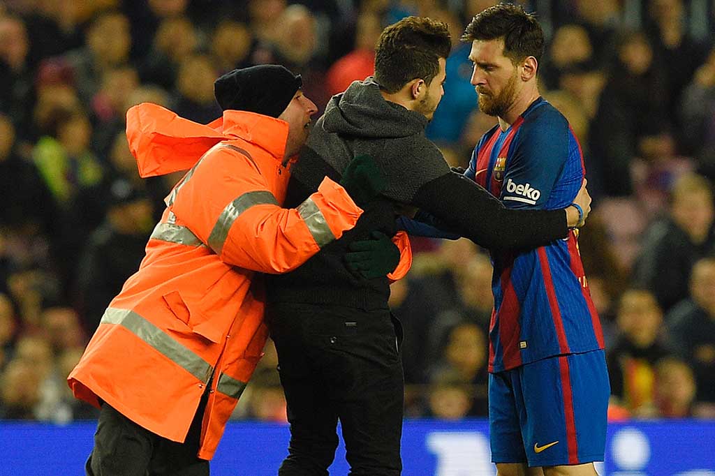 Ofisial pertandingan menahan seorang suporter yang berusaha mendekati Lionel Messi.