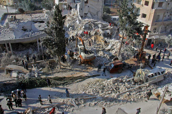 Warga bersama sukarelawan dibantu alat berat berusaha mencari korban di antara puing-puing bangunan, menyusul serangan udara di barat laut Suriah, Idlib, Selasa