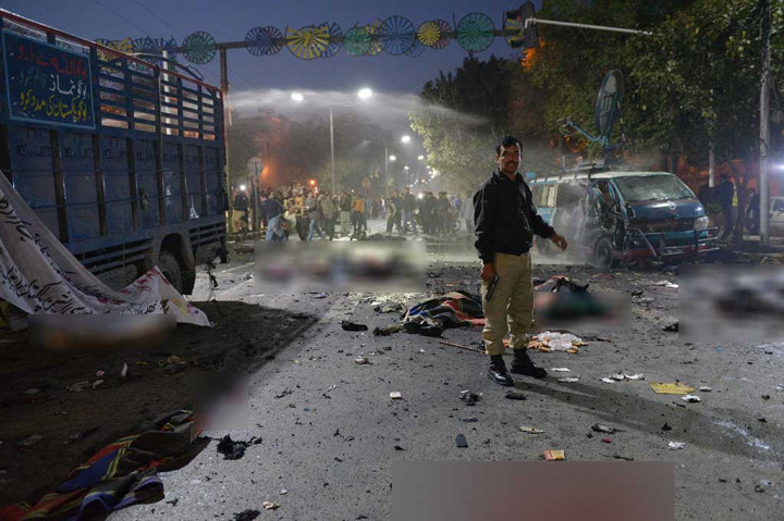 Seorang anggota polisi Pakistan berdiri di lokasi ledakan bom di Lahore, Pakistan, Senin waktu setempat.