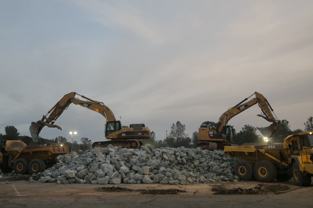 Ekskavator memindahkan bongkahan pecahan batu yang akan dipakai sebagai tanggul darurat.