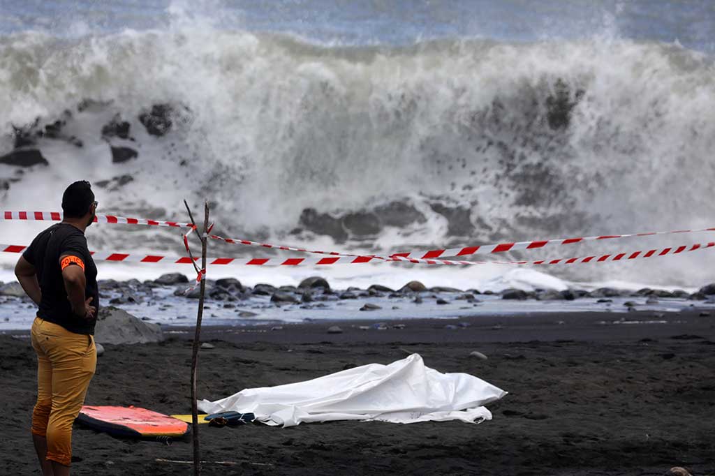 Seorang polisi berdiri di dekat jenazah pria yang diserang hiu di lepas pantai La Reunion, Samudra Hindia, Selasa (21/2/2017) waktu setempat.