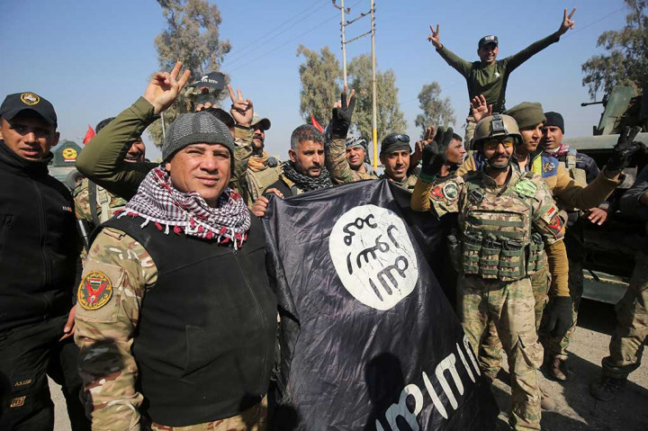 Pasukan Irak merayakan kemenangan mereka sambil memegang bendera kelompok IS yang ditinggalkan para militan.