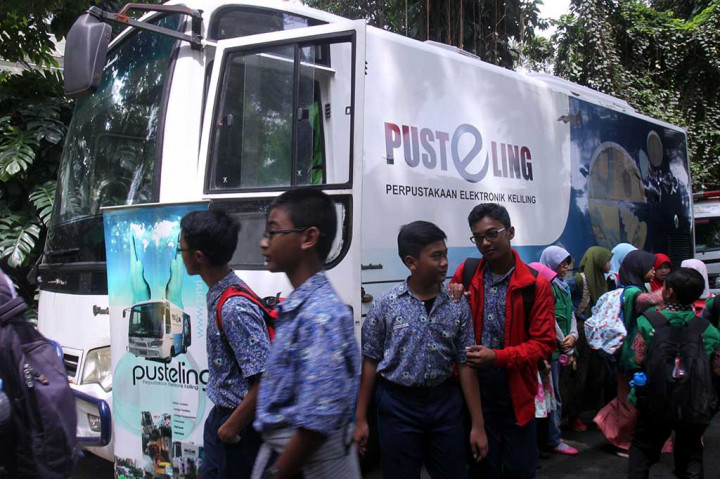 Sejumlah siswa Sekolah Dasar berjalan di depan dekat Layanan Perpustakaan Elektronik Keliling (Pusteling) di kawasan Kebun Raya Bogor, Kota Bogor.