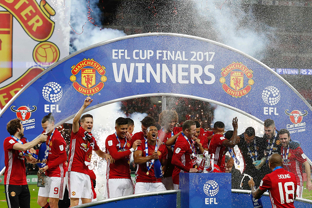 Para pemain MU melakukan selebrasi dengan mengangkat trofi Piala Liga Inggris.