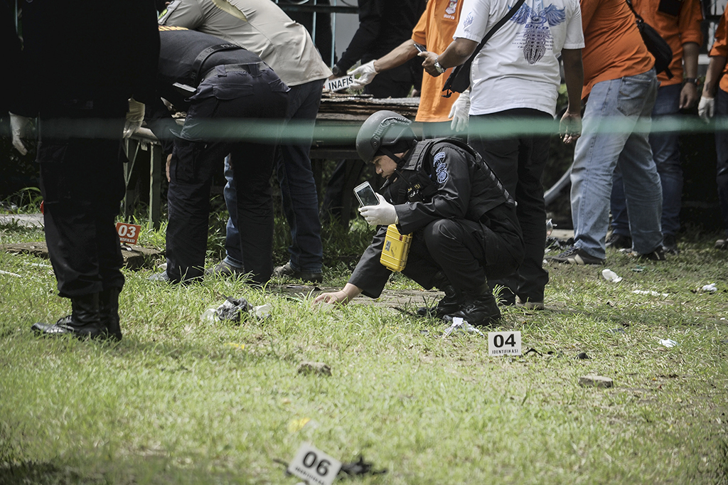 Para petugas memeriksa serpihan bom yang masih terlihat di tempat pengeboman berupa sisa bahan alumunium sejenis panci dan serbuk berwarna putih juga paku-paku yang bertebaran di sekitar TKP.