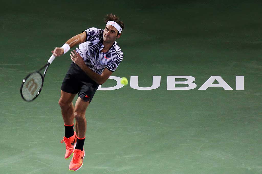 Petenis Swiss Roger Federer melancarkan servis ke arah lawannya Benoit Paire, pada putaran pertama Dubai Terbuka di Dubai, Senin (27/2/2017).