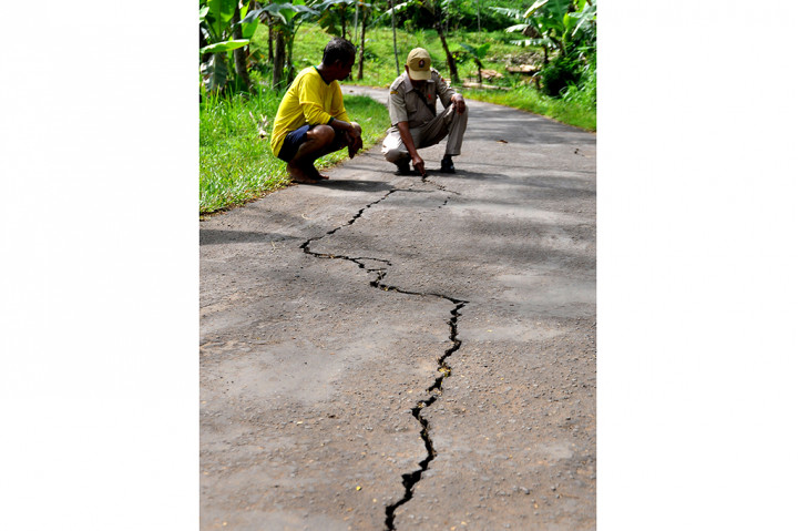 Tanah bergerak juga menimbulkan retakan di jalan sepanjang 25 meter.