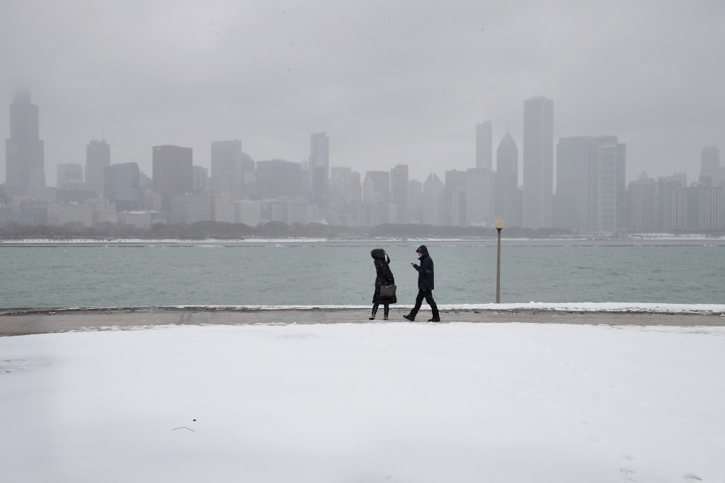 Warga berjalan-jalan di sebuah taman di Chicago, Illinois, yang tertutup salju. Ketebalan salju yang turun dalam badai dilaporkan hingga lebih dari 10 centimeter. Scott Olson/Getty Images/AFP