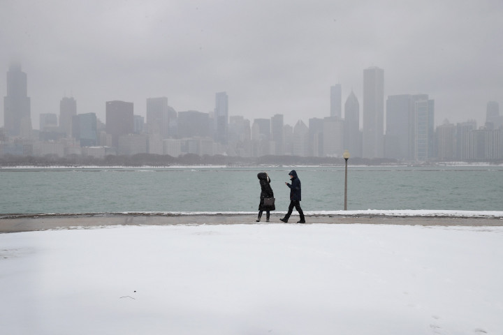 Warga berjalan-jalan di sebuah taman di Chicago, Illinois, yang tertutup salju. Ketebalan salju yang turun dalam badai dilaporkan hingga lebih dari 10 centimeter. Scott Olson/Getty Images/AFP