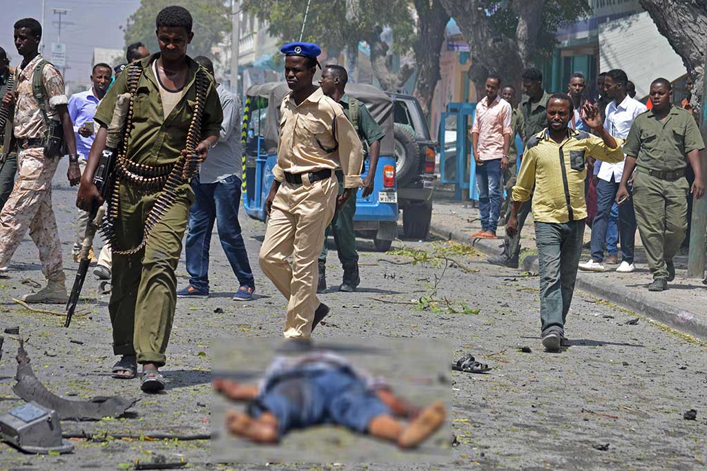 Petugas keamanan berjalan di dekat jenazah korban ledakan bom di Mogadishu, Senin. 