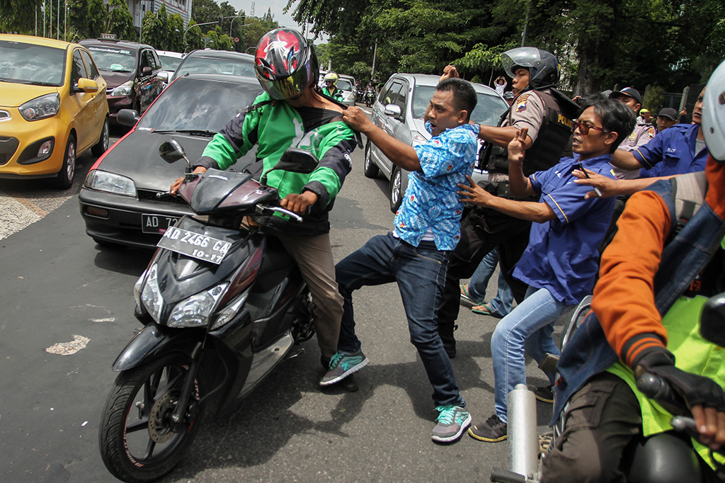 Polisi menghadang pengemudi Go-jek yang terlibat ricuh dengan pengemudi taksi saat berlangsung unjuk rasa menolak operasi Go-jek di Balaikota Solo, Jawa Tengah.