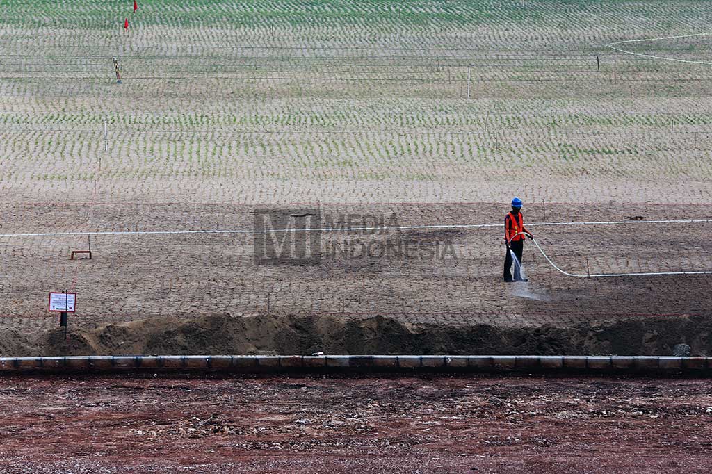 Pekerja menyirami rumput stadion pada  proyek renovasi Stadion Utama Gelora Bung Karno (SUGBK).