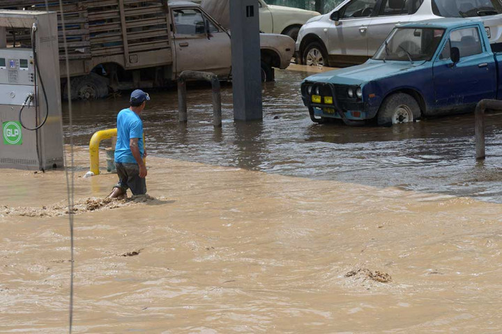 Seorang warga berjalan menerjang banjir yang merendam Distrik Huachipa, Lima.