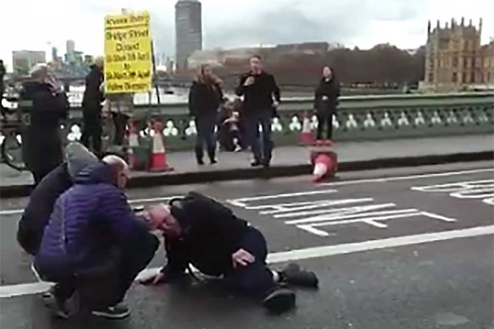 Gambar yang diambil dari video menunjukkan seorang pria mendapatkan pertolongan pascaserangan sebuah mobil yang menabrak pejalan kaki di Jembatan Westminster, dekat gedung parlemen Inggris, London, Rabu (23/3/2017) waktu setempat. AFP/Radosaw Sikorski