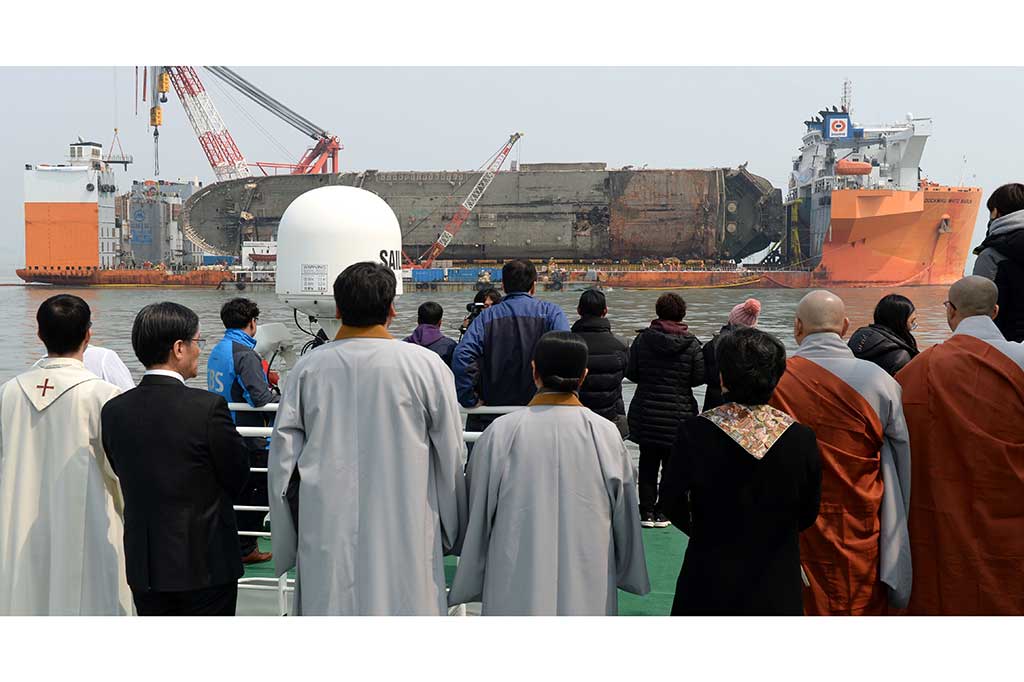 Keluarga korban bersama beberapa pemuka agama memanjatkan doa saat bangkai Sewol berhasil diangkat dari dasar laut di perairan Jindo pada Selasa (28/3/2017) lalu.