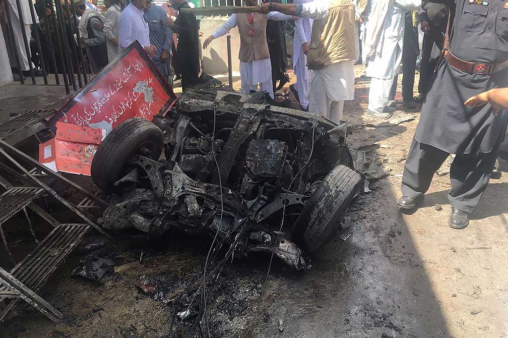 Warga melihat sebuah mobil yang hancur terkena bom di sebuah pasar di Parachinar, Pakistan, Jumat (31/3/2017).