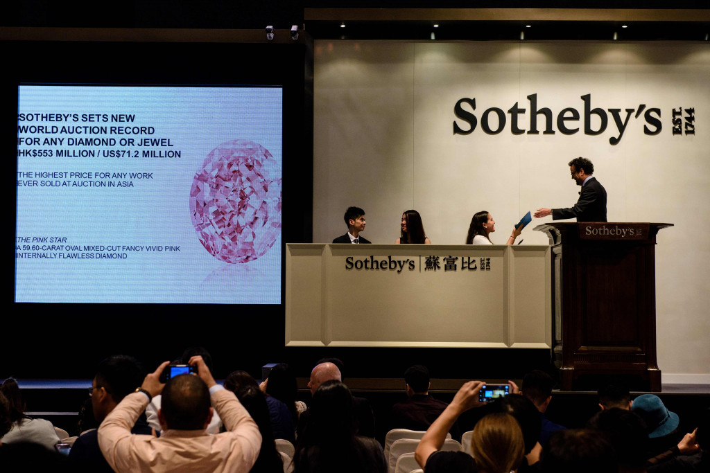 Kepala Divisi Internasional Perhiasan Sotheby, David Bennett (kanan), menyerahkan sertifikat untuk berlian yang bernama Pink Star. Berlian dijual dalam lelang yang diadakan Balai Lelang Sotheby.