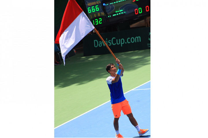 Petenis Indonesia Christopher Rungkat mengibarkan bendera merah putih usai mengalahkan petenis Kuwait Abdullah Maqdes pada pertandingan Piala Davis Grup II Zona Asia/Oceania.
