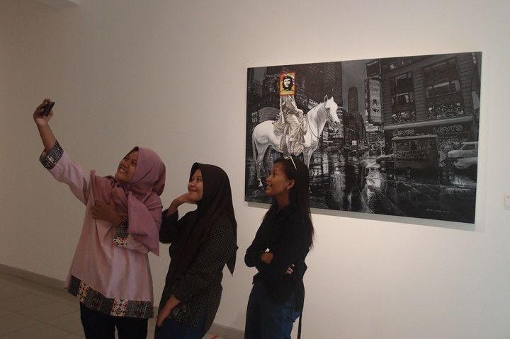 Pengunjung berswafoto dengan lukisan karya pelukis Triyadi Guntur Wiratno bertajuk 