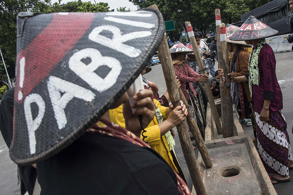Mereka berpakaian khas petani dan mengenakan topi petani bertuliskan 'Tolak Pabrik Semen'.