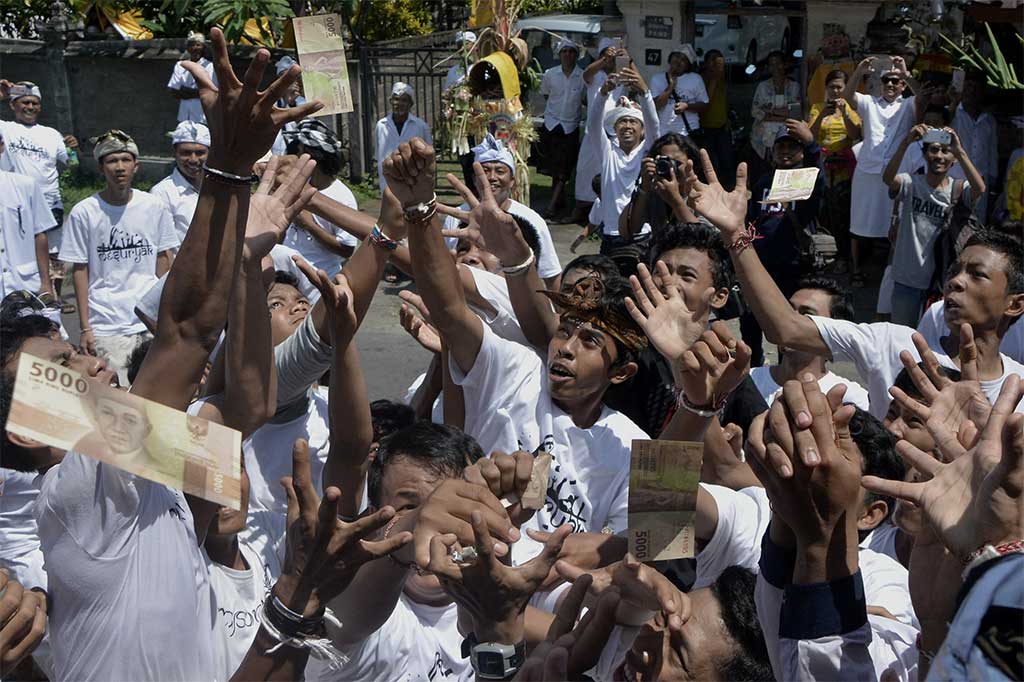 Warga saling berebut uang yang dilempar saat Tradisi Mesuryak.