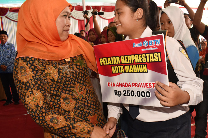 Menteri Sosial Khofifah Indar Parawansa (kiri) menyerahkan beasiswa kepada pelajar berprestasi. Pencairan akan dilakukan empat kali dengan nilai tiap keluarga penerima manfaat mendapat Rp1.890.000.