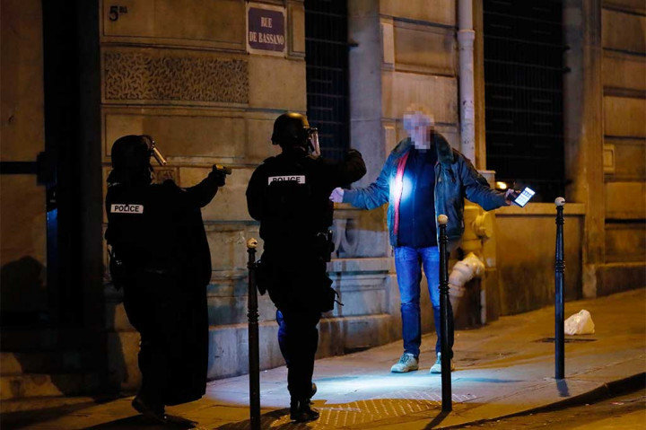 Polisi memeriksa seorang pria di sebuah jalan di dekat Champs Elysees, Paris.