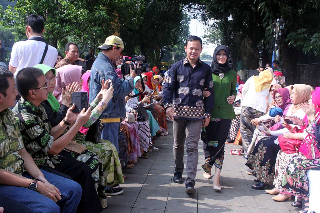 Wali Kota Bogor Bima Arya (kiri) bersama istri Yane Ardian memperagakan pakaian dengan motif batik angkot yang diluncurkan di pedestrian sekitaran Tugu Kujang, Kota Bogor, Jawa Barat, Sabtu (22/4/2017).