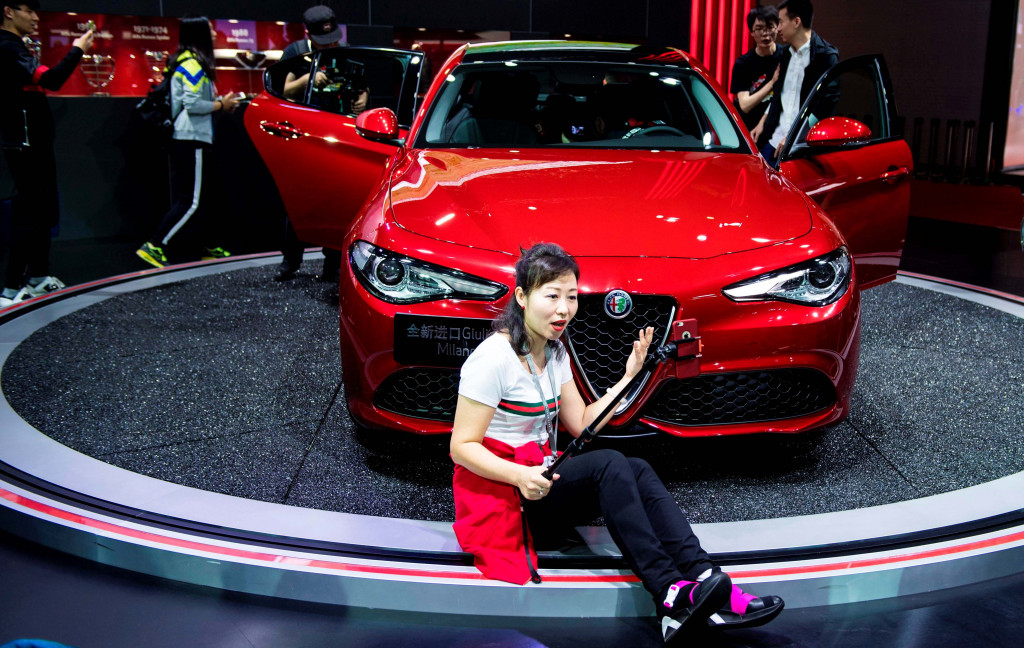 Alfa Romeo Guilia Milano warna merah menyala dari Italia jadi pilihan seorang pengunjung wanita berswafoto. Mobil mewah warna merah menjadi favorit di Tiongkok yang punya banyak 'orang kaya baru'.