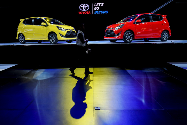 Seorang pengunjung pameran melintasi booth Toyota yang memajang dua model generasi baru Agya.  Antara Foto/Hafidz Mubarak