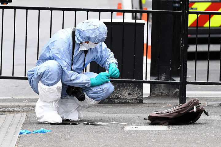 Petugas forensik melakukan penyelidikan pada sebuah tas hitam yang berisi tiga buah pisau milik pria tersebut.