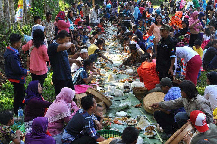 Warga menyantap makanan yang dibawa secara bersama-sama.