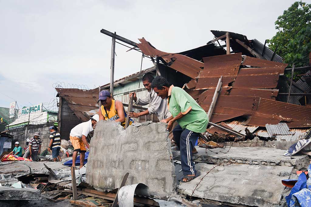 Pekerja menyingkirkan puing-puing dari rumah yang roboh pascagempa berkekuatan 6,8 SR mengguncang General Santos City, Pulau Mindanao, Sabtu (29/4/2017). 