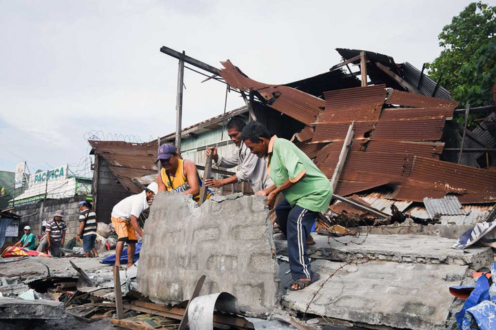 Pekerja menyingkirkan puing-puing dari rumah yang roboh pascagempa berkekuatan 6,8 SR mengguncang General Santos City, Pulau Mindanao, Sabtu (29/4/2017). 