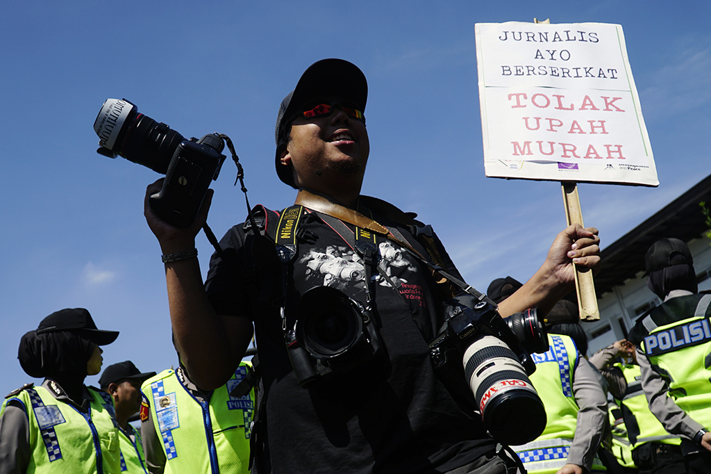 Pewarta foto yang tergabung dalam Solidaritas Jurnalis Bandung membawa poster saat memperingati Hari Buruh di depan Gedung Sate, Bandung, Jawa Barat.