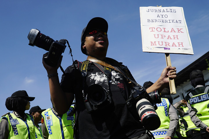 Pewarta foto yang tergabung dalam Solidaritas Jurnalis Bandung membawa poster saat memperingati Hari Buruh di depan Gedung Sate, Bandung, Jawa Barat.