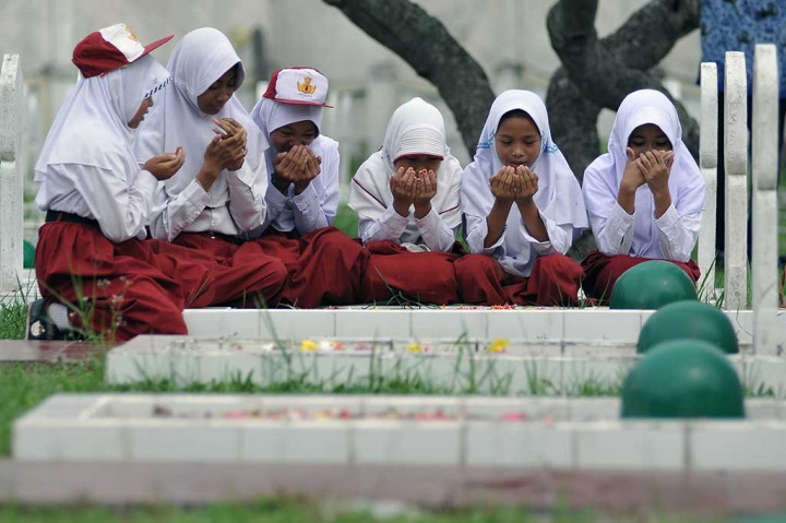Pelajar Sekolah Dasar (SD) berdoa usai menaburkan bunga di salah satu makam di Taman Makam Pahlawan Satria Bhakti, Jambi, Selasa (2/5/2017) dalam rangka memperingati Hari Pendidikan Nasional (Hardiknas). ANTARA/Wahdi Septiawan