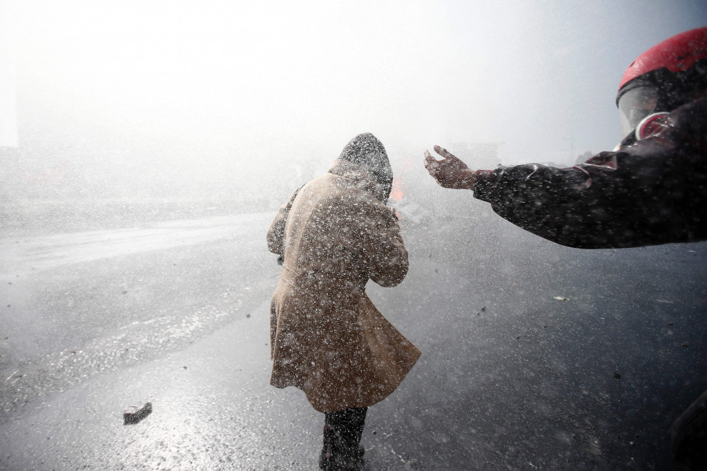 Seorang buruh mengindar dari semburan water cannon untuk membubarkan pengunjuk rasa.