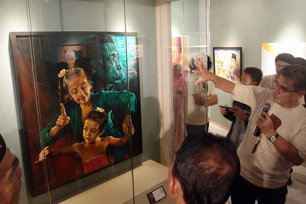 Pelukis Yoannes Pranowo (kanan) menerangkan karya lukisannya berjudul Merawat Bibit, yang merupakan salah satu dari 10 lukisan terbaik pada Pameran Lukisan Para Guru se-Jabodetabek, di Museum Basoeki Abdullah.