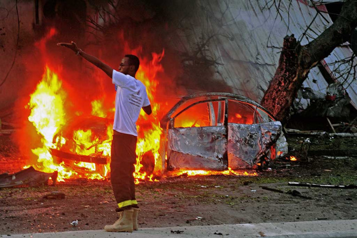 Seorang petugas pemadam kebakaran memberi isyarat kepada teman-temannya untuk secepatnya memadamkan api di lokasi serangan bom mobil di Mogadishu, Somalia, Senin (8/5/2017) waktu setempat.