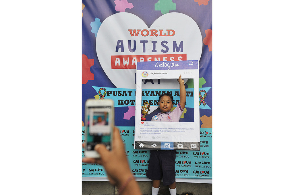 Anak berkebutuhan khusus berfoto di depan baliho saat turut dalam peringatan Hari Autisme se-dunia di Denpasar, Selasa (9/5/2017). 