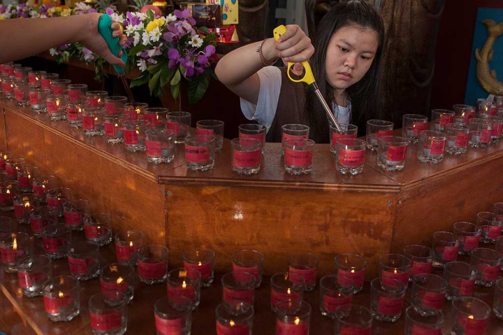 Seorang Umat Buddha menyalakan lilin pada prosesi kebaktian Bodhisattwa Sidharta di Wihara Buddha Dharma, Kuta, Bali.