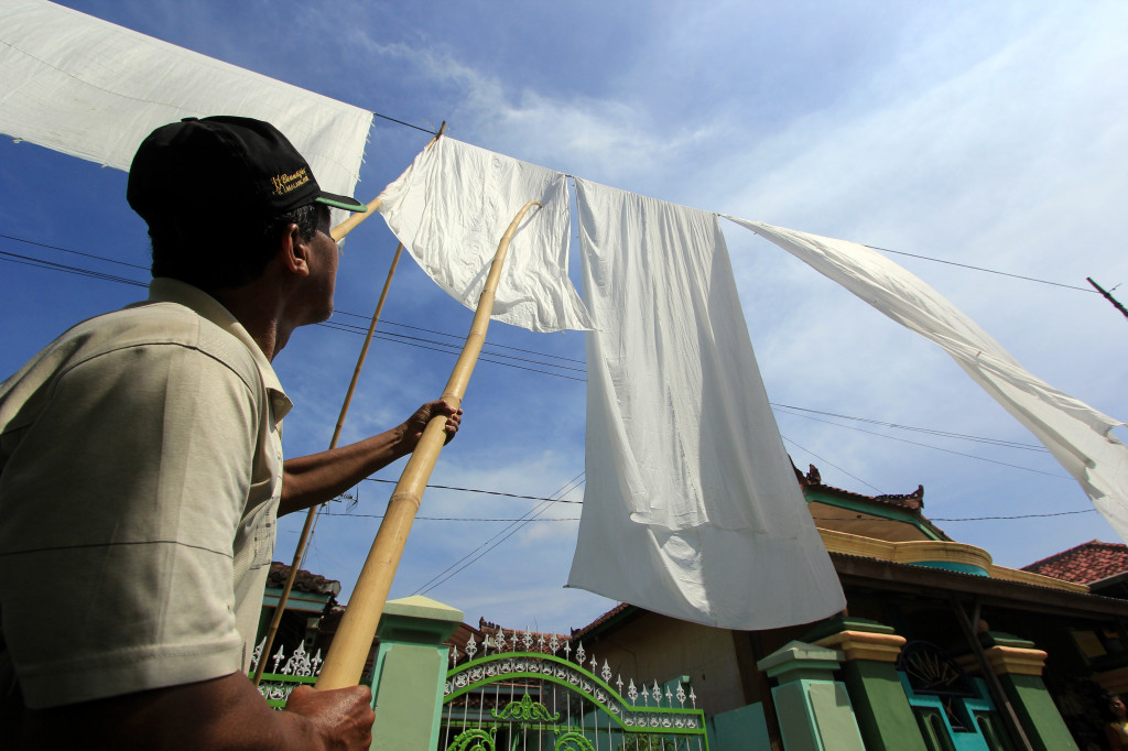 Warga menjemur kain kafan saat ritual Resik Lawon (membersihkan kain kafan) di Cungking, Banyuwangi, Jawa Timur, Kamis (11/5/2017).