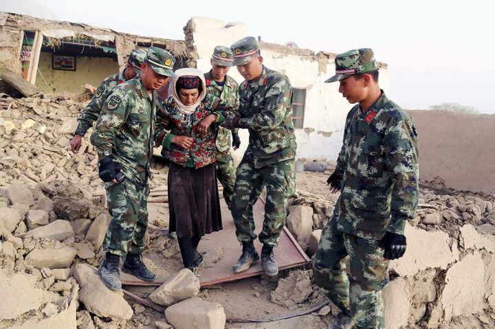 Petugas polisi paramiliter Tiongkok membantu seorang wanita keluar dari rumahnya yang rusak akibat diguncang gempa di daerah Taxkurgan, Prefektur Kashgar, Xinjiang, bagian barat laut Tiongkok, Kamis (11/5/2017).