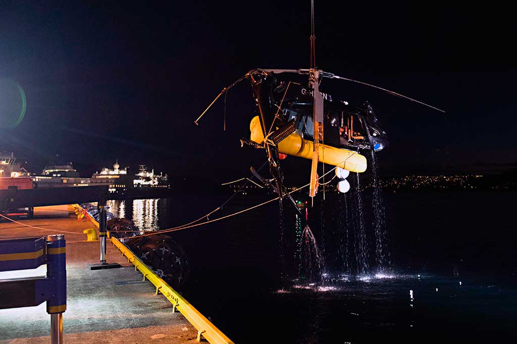 Petugas dibantu alat berat berusaha mengevakuasi sebuah helikopter yang terjun ke laut di dekat pelabuhan Bergen, Norwegia, Kamis (11/5/2017) malam waktu setempat. 