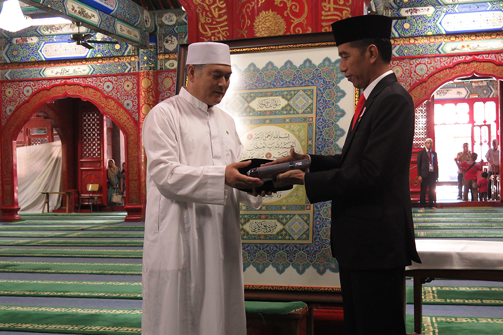 Presiden Joko Widodo memberikan cendera mata berupa songkok dan sarung kepada imam Masjid Niujie, Beijing, Ali Yang Gunjun.