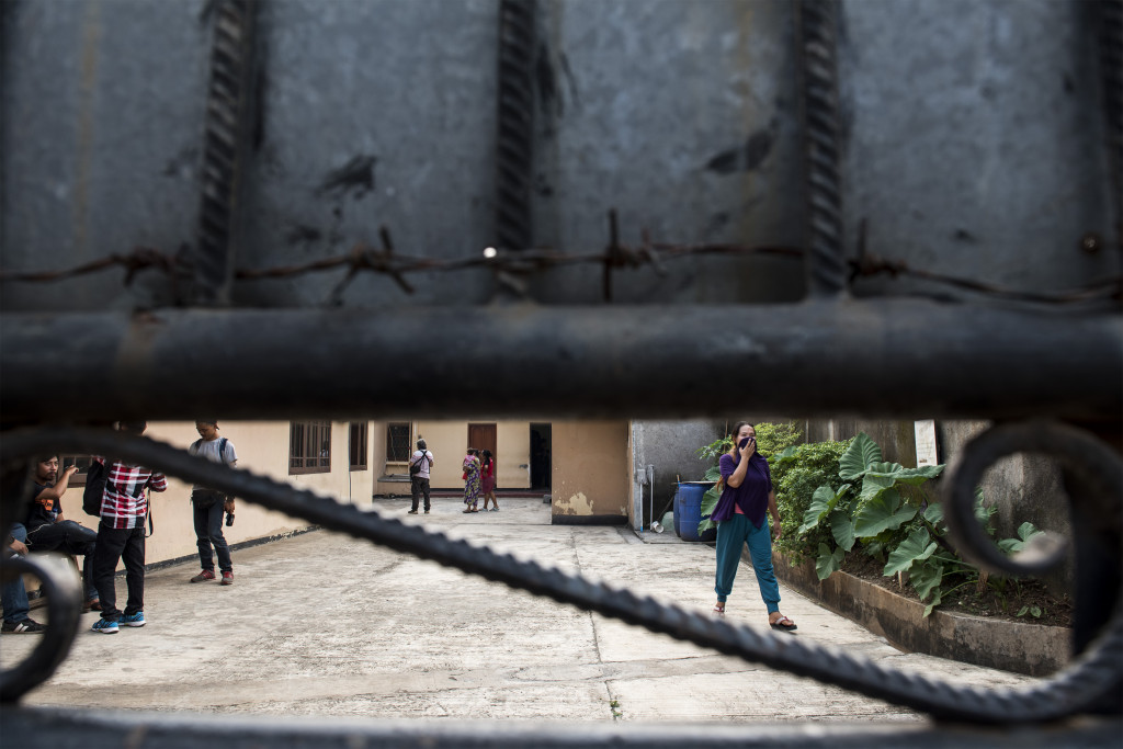 Warga melintas di balik pagar gedung tempat penampungan. Polisi menemukan dokumen-dokumen pengurusan visa umroh, ziarah dan cleaning service yang diduga untuk selundupkan calon TKI ke negara tujuan. 