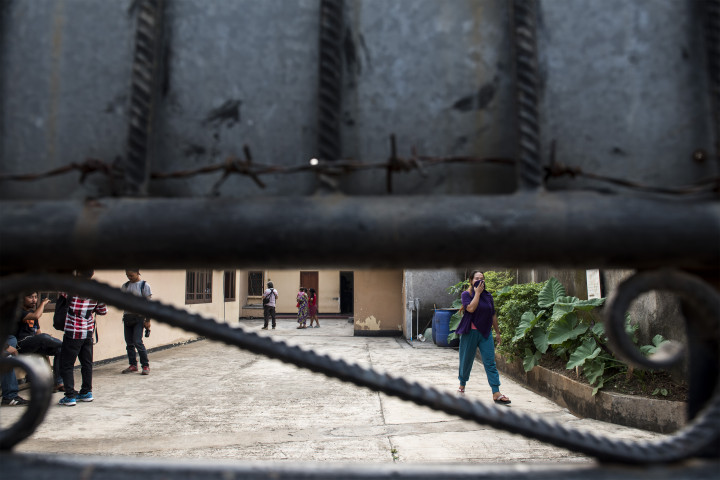 Warga melintas di balik pagar gedung tempat penampungan. Polisi menemukan dokumen-dokumen pengurusan visa umroh, ziarah dan cleaning service yang diduga untuk selundupkan calon TKI ke negara tujuan. 
