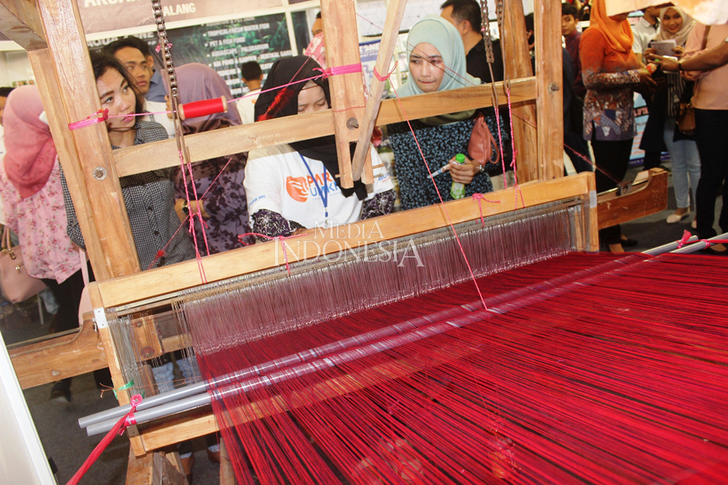 Sejumlah pengunjung sangat antusias melihat para perajin dalam menenun kain sekaligus tergerak untuk belanja produk UMKM di arena Parade UMKM BRI, Kota Malang, Jawa Timur.