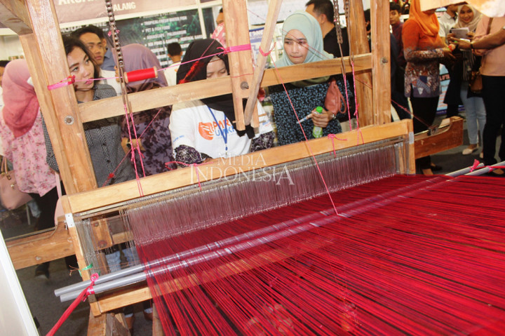 Sejumlah pengunjung sangat antusias melihat para perajin dalam menenun kain sekaligus tergerak untuk belanja produk UMKM di arena Parade UMKM BRI, Kota Malang, Jawa Timur.